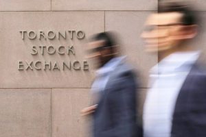 Businessmen pass the Toronto Stock Exchange sing in Toronto