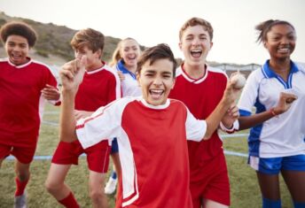 Middle School kids playing soccer together.