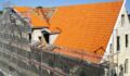 A restoration of tiles on the roof of a brick house.