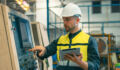 Worker and engineer using tablet computer for inspection and checking production process on factory station.