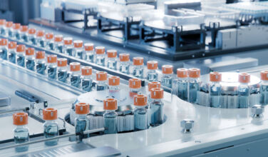 Vaccine Production Facility. Medication Manufacturing Process. Glass Vials with Orange Caps on Conveyor Belt. Medical Ampoule Production Line at Modern Pharmaceutical Factory.