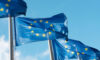 Row of blue EU flags in Brussels. The blue flags have twelve yellow stars depicting the original number of member states.