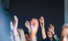 Engaged Audience Raising Hands at Business Event