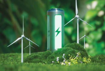 Photo of a green eco-battery surrounded by forestry and windturbines.