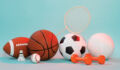 A pile of various sports equipment including a basketball, a shuttlecock and some weights