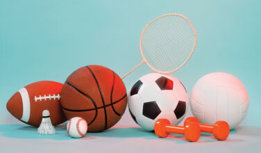 A pile of various sports equipment including a basketball, a shuttlecock and some weights