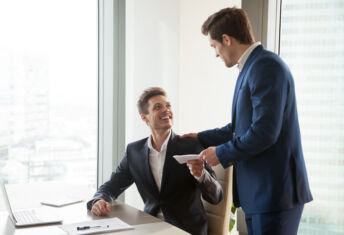 PE targets healthcare benefit management: 5 deals General manager presenting an envelope with premium or bonus cash to male company official. Boss congratulating happy employee with career promotion, thanking for good job and giving financial reward