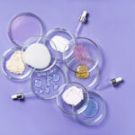 Cosmetic products, scrub, face serum and gel in many petri dishes on a pink background. Cosmetics laboratory research concept.