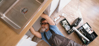 plumber fixing the sink in the kitchen Getty